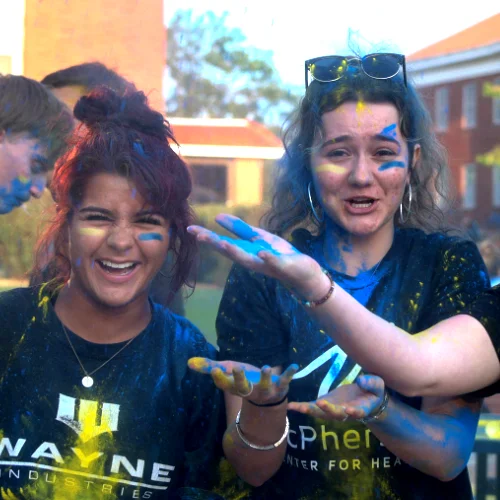 Students laughing and celebrating during a colorful campus event at Central Christian College, showcasing friendship, school spirit, and student life.