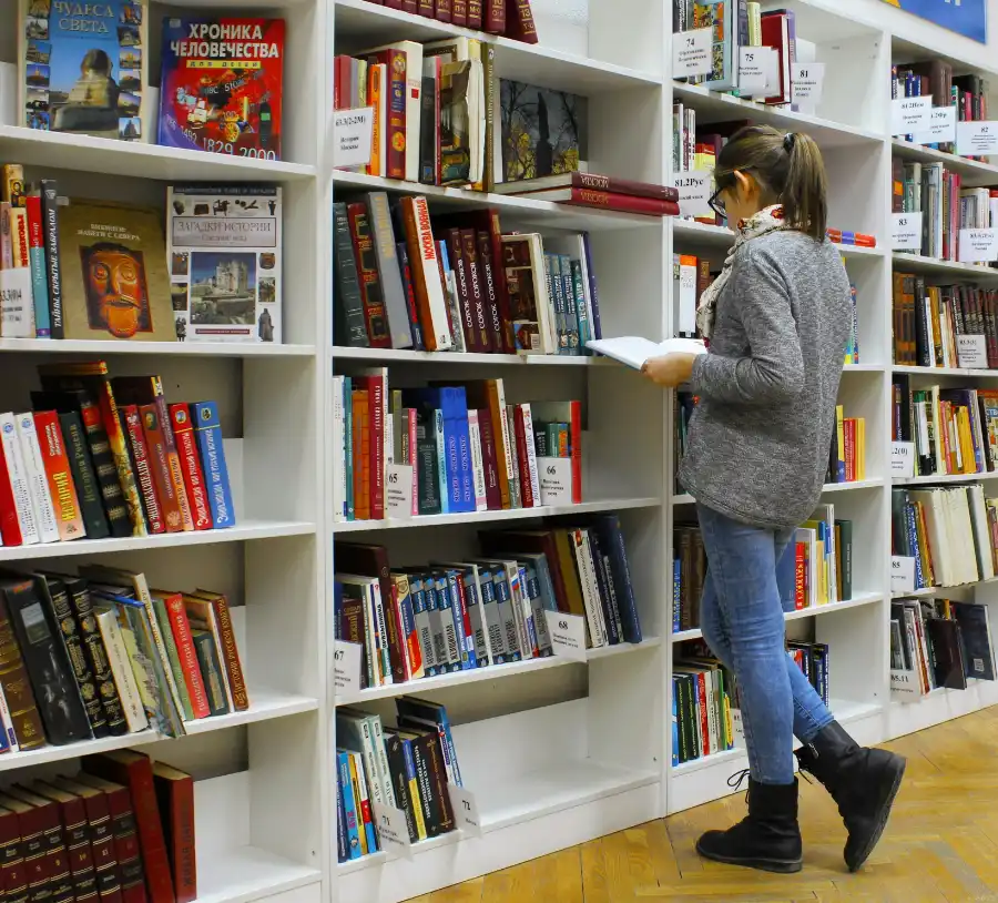 Student browsing books and studying in a campus library at Central Christian College, highlighting academic focus, research, and quiet learning spaces.