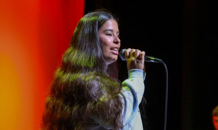 Student singer performing on stage under colorful lighting at Central Christian College, highlighting creative arts, confidence, and campus talent.