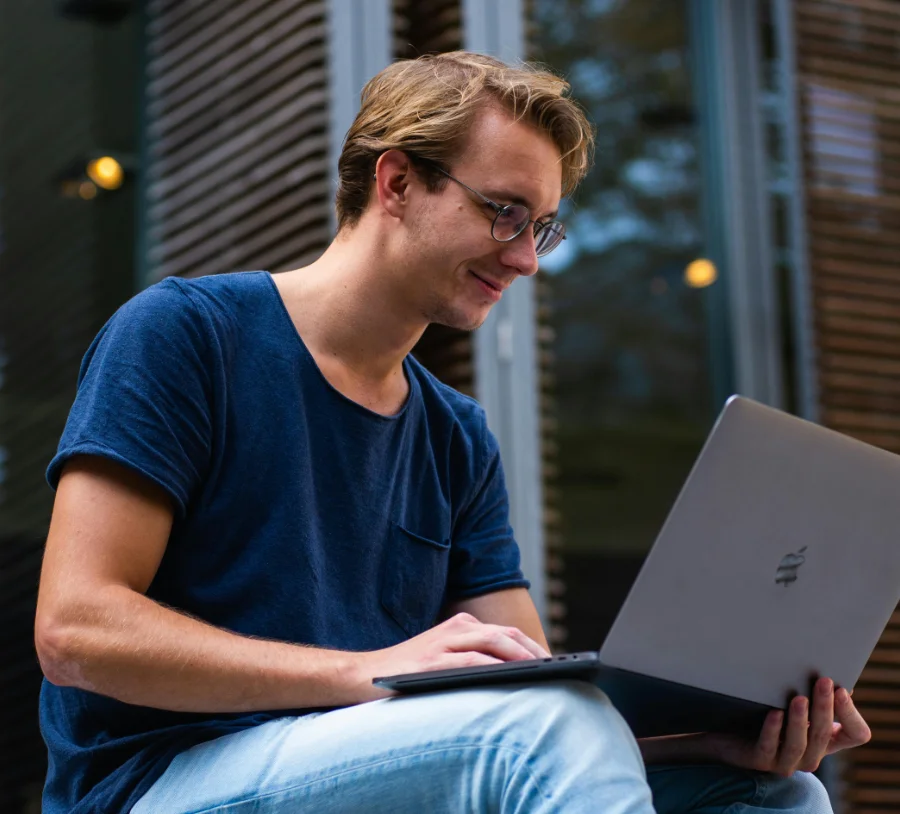 College student studying on a laptop outdoors at a Christian College, highlighting flexible learning and campus life.