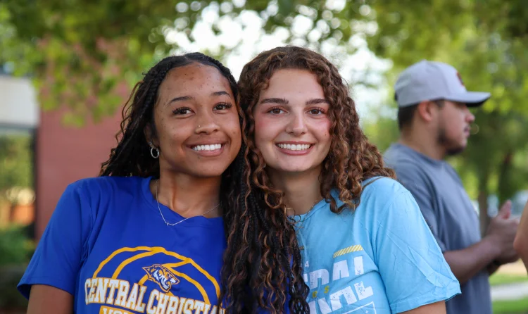 Two smiling students wearing Central Christian College shirts on campus at a Christian College Kansas, representing community, faith, and student life.